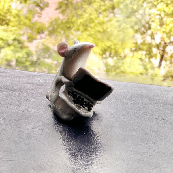 Tiny clay rat with laptop A photo of a tiny clay rat holding a laptop